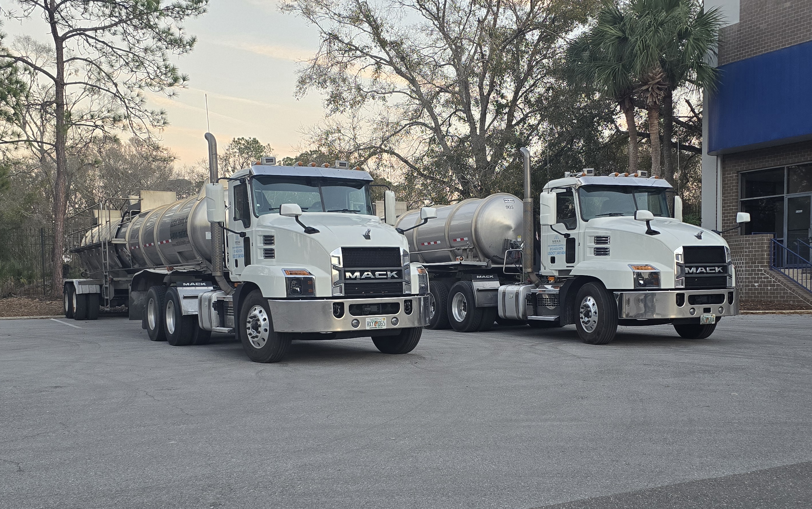 Two white Mack tanker trucks side by side
